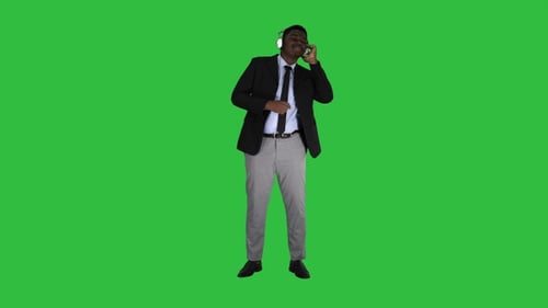 Black Businessman Dancing to Music in Headphones on A Green