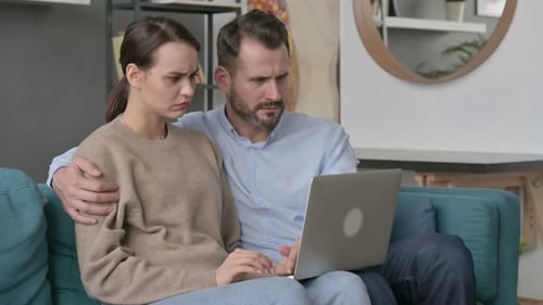 Frustrated Couple Using Laptop at Home on Couch