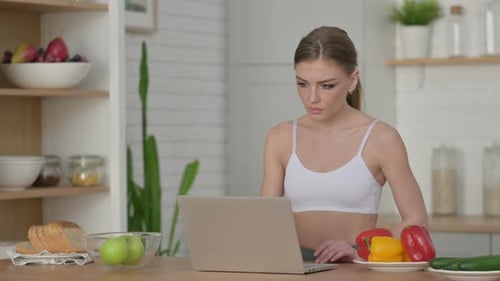 Young Adult Woman Working on Laptop in Kitchen
