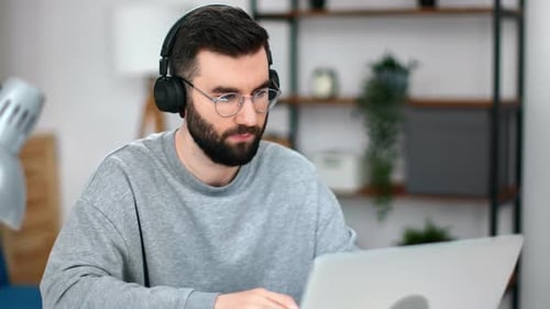 Man With Headphones Works on Laptop in Office