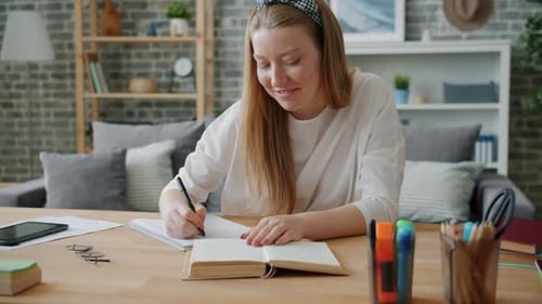 Woman Studying and Writing in a Notebook