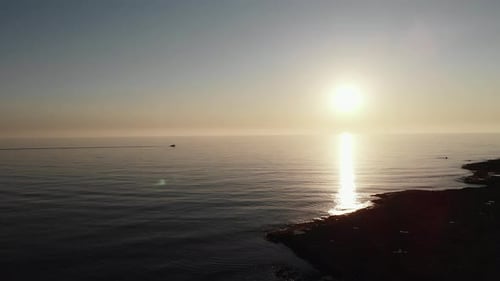 Silhouette of Fast Motor Boat Riding Towards Sunset at Sea with Sun Road Reflection on Water
