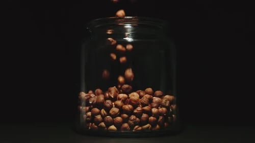 SLOW MOTION: Peeled Nuts Falling Into A Glass Jar