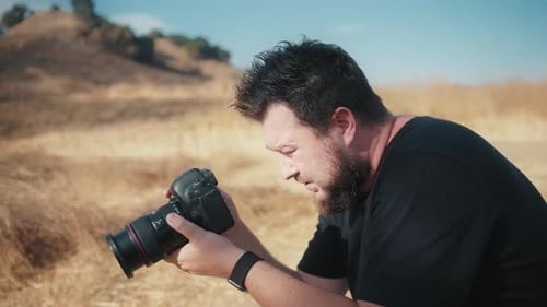 Man Taking Photos in Rural Field with DSLR Camera