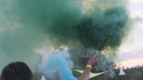 Person Holding a Green Smoke Grenade at Event