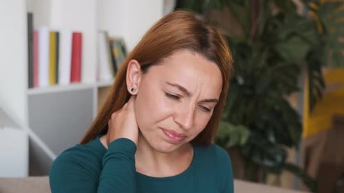 Nahaufnahme der jungen Frau, die ihren Hals zurückhält, während sie Kopfschmerzen hat