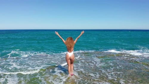 Young Woman in Bikini on Sea Shore and Splashing Water Waves Aerial Landscape. Beautiful Woman on