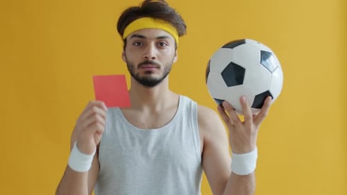 Slow Motion Portrait of Attractive Arab Guy Holding Football Showing Red Card