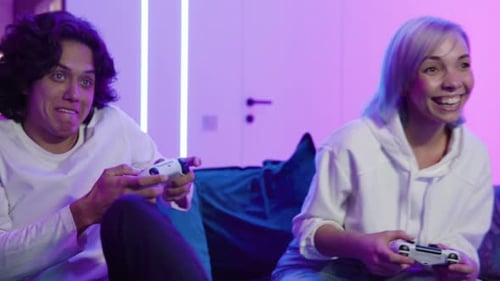 Couple Plays Video Games at Home on Sofa