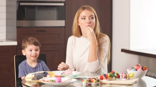 Woman Decorating Easter Eggs with Little Son