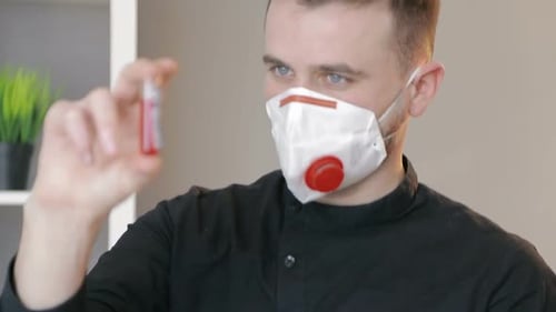 Primer plano de un tubo de ensayo con un análisis de sangre de coronavirus en la mano del médico. La cara del doctor es