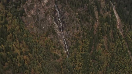 Aerial Shot of Waterfall By the Rocky Side of Mountain Surrounded By Trees