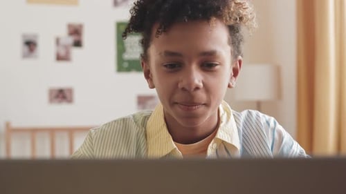 Smiling Child Looking at Laptop at Home