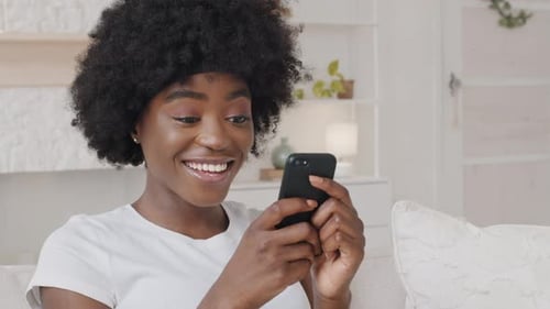 Woman Looks at Mobile Device and Smiles