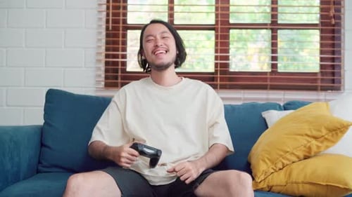 Man Playing Video Game at Home on Sofa