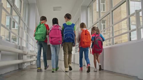 Children With Backpacks Walk School Hallway Away From Camera