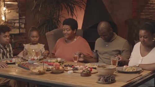 Family Holds Hands and Prays Before Dinner