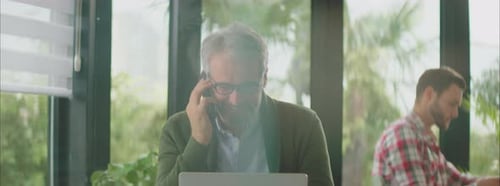 Man Talking on Phone While Working on Laptop