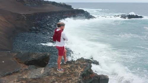 Man Observes a Magnificent Scenery of the Coast Surrounded By the Ocean Waters