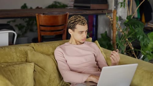 Young Adult Uses Laptop and Phone at Home