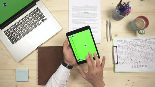 Man Using Tablet with Green Screen on Desk