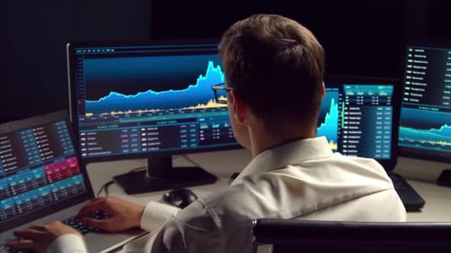 Händler, der nachts im Büro arbeitet und Workstation- und Analysetechnologie verwendet.