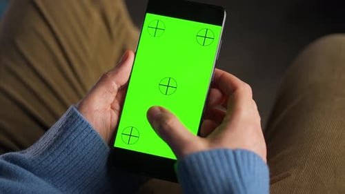 Man Using Smartphone with Green Mockup Screen in Vertical Mode