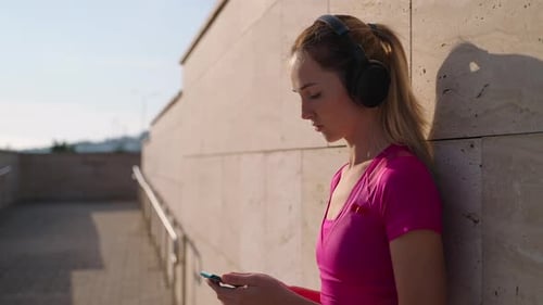 Blond Woman Using Phone While Leaning on Wall