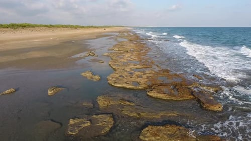 Flaches Felsenriff zwischen Meer und Strand