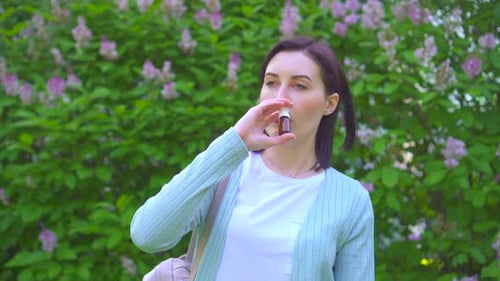 Woman Using Nasal Spray in Blooming Spring Park