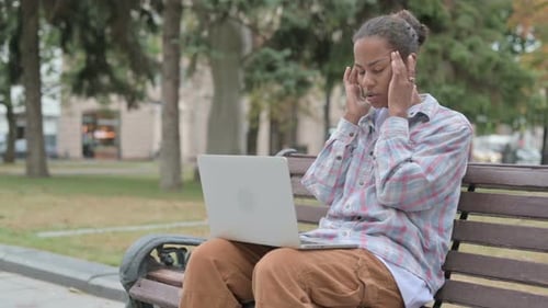 Woman Using Laptop Outdoors on Park Bench