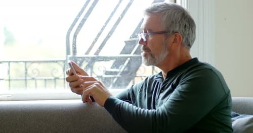 Man using mobile phone in living room 4k