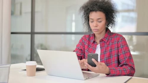 Woman Using Laptop and Cell Phone at Desk