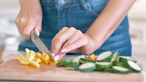 Close Up Of Woman Cutting Vegetables In Kitchen