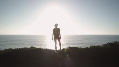 Silhouette of Woman Overlooking Ocean at Sunrise