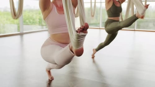 Young Women Practicing Aerial Yoga in Bright Studio