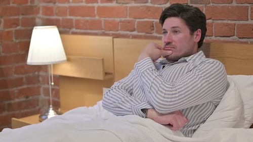 Pensive Man Lies Awake in Bed Thinking