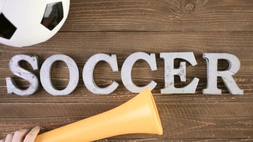 Metal letters Soccer vuvuzela stadium horns on a wood background.