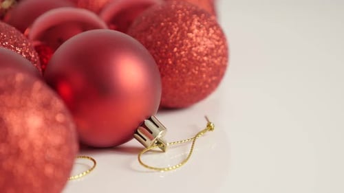 Lot of red Christmas baubles on white 4K slow tilt video