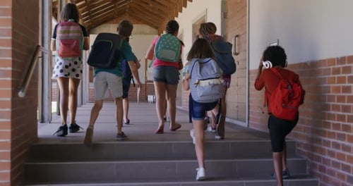Group of kids with school bags walking in the school corridor