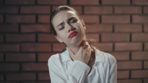 Unhappy Woman Feeling Sore Throat and Coughing on Brick Wall Background