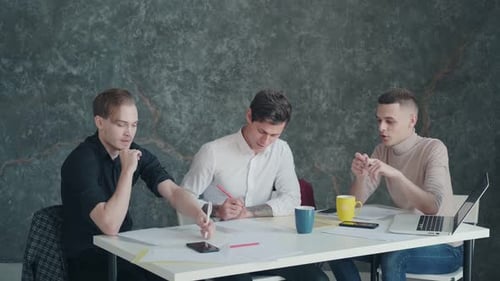 Trois hommes discutent d'un projet et d'un plan alors qu'ils sont assis à une table dans un bureau