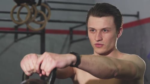 Junger Mann ohne Hemd trainiert mit einer Kettle Bell