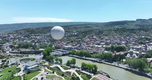 Flying over white balloon in the center of city. Morning cityscape of Tbilisi