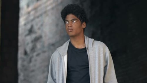 Upset Afro-American teen male walking on building ruins