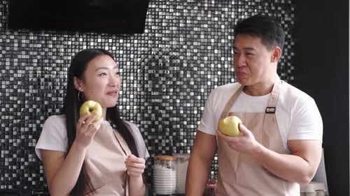 Woman and Man in Kitchen Holding Apples