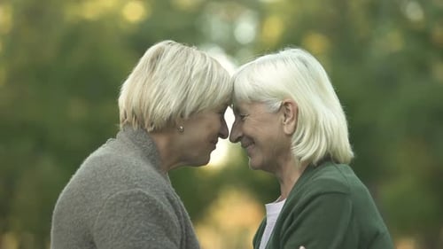 Senior Women Touching Foreheads and Embracing Outdoors
