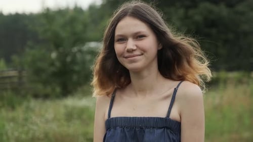 Smiling Young Woman with Long Brown Hair Outdoors
