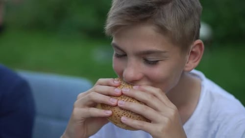 Teen Enjoys a Delicious Burger in Sunlight