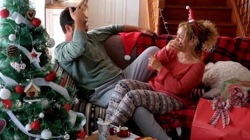 Couple Laughing Together on Sofa During Christmas